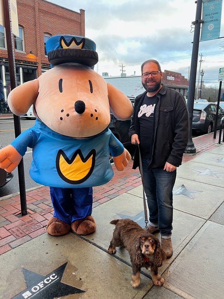 Cocoa Puff standing with her owner and "Dog Man" the mascot.