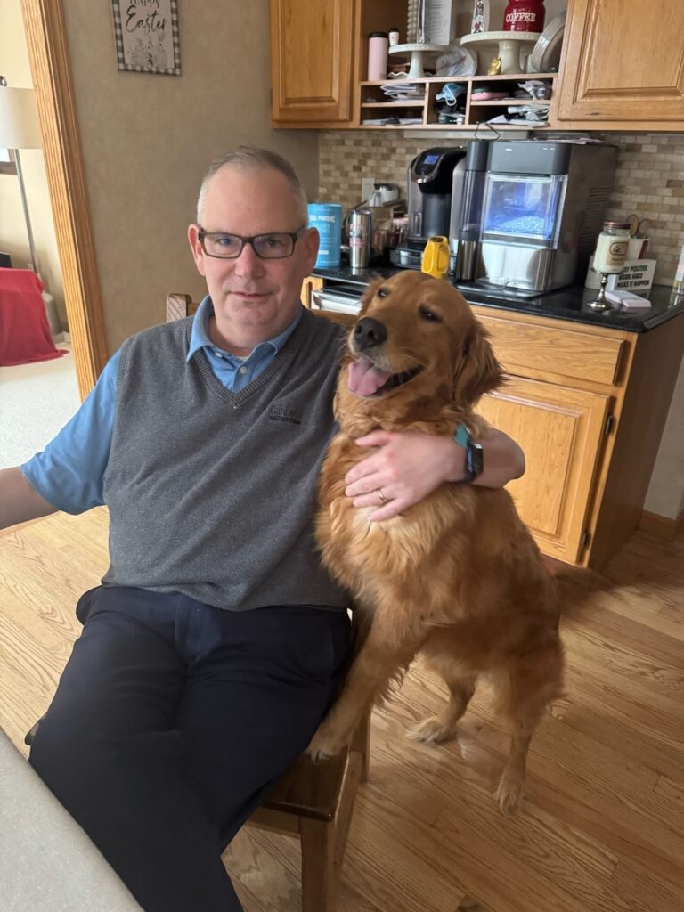 Oakley with her owner, hugging at the kitchen table.