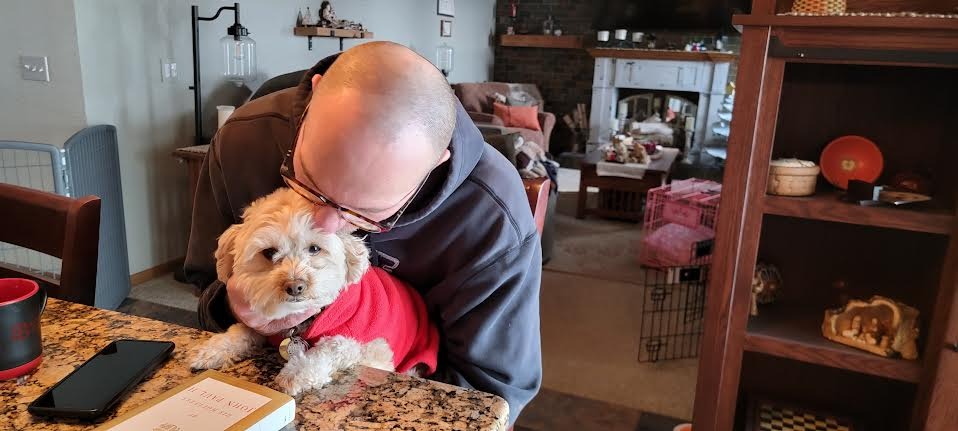 Sid in red sweater with adoptive parent hugging him.